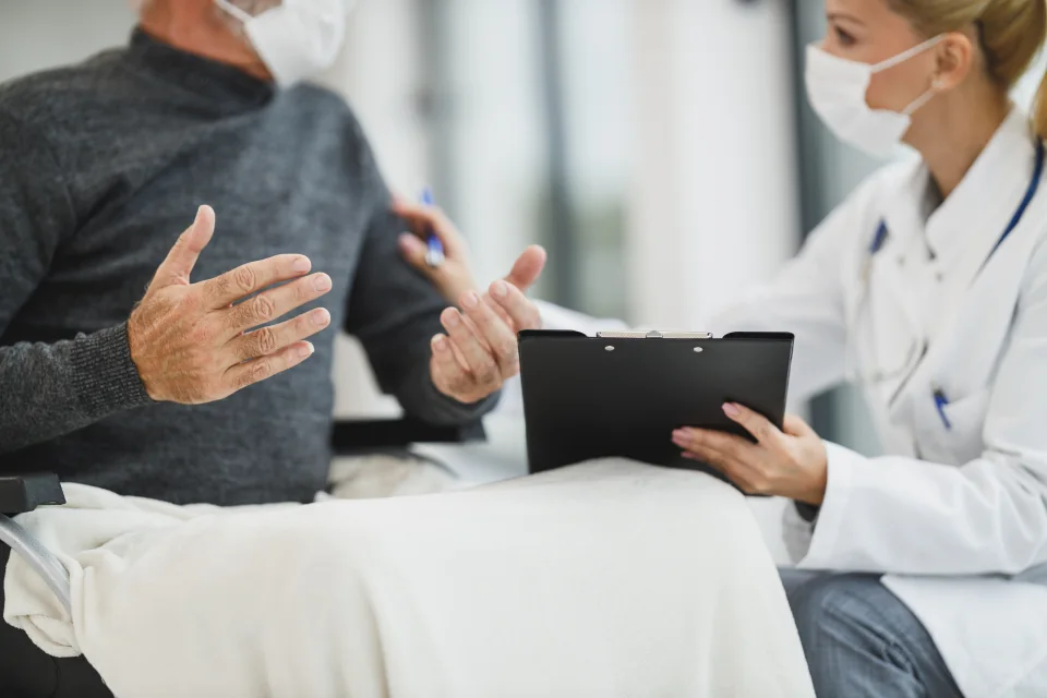 A doctor listening to an older patient describe their condition